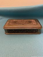 Closed view of vintage rectangular silver metal jewelry box showing ornate embossed detail on lid and sides.
