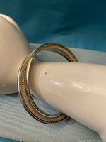 Side view of sterling silver cuff bangle bracelet showing half mesh and half solid design on a display hand.