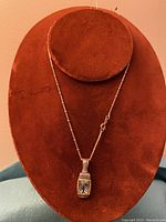 Front view of the sterling silver necklace with pendant on red stand.