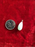 Photo of the jade pendant and a Canadian quarter for size reference, placed on a red velvet background.