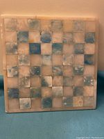 Full view of the marble chess board showing the entire square tile pattern.