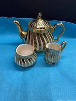 Photo of vintage Sadler tea pot set including tea pot, creamer, and sugar bowl with gold and white swirl design