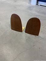 Pair of teak wood and brass bookends viewed from front and side, showing shape and materials.