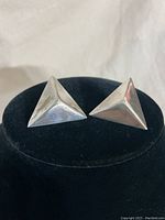 Front view of the pair of sterling Art Deco triangular dimensional earrings on black display stand.