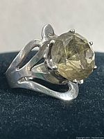 Front angle close-up of the sterling silver ring showing the light olive green stone and split shank band design.