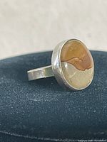 Close-up of the sterling silver ring showing the round brown and olive stone with natural patterns, set in a solid bezel.
