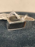 Close-up of rectangular black onyx stone in the sterling silver ring, showing side profile and surface texture.