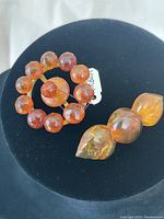 Overview of both amber brooches on black background showing bead details and metal backs