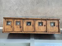 Front view showing six cubby doors with glass windows and paper letter tags, wood surface with worn finish