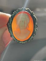 Front view of the cameo ring showing the carved white figure on orange stone with silver frame.