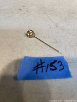 Gold stick pin with helmet design and enamel, shown full length on a white surface with #153 tag.