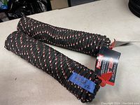 Two black braided utility ropes with red and white speck pattern, coiled and tagged with 'Tuff Rope' brand and specifications.