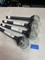 Four mini solar pathway lights with black stakes and crackled clear glass globe tops laid on a table