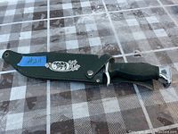 Photo of Bowie cutting knife sheathed to show sheath design and handle pommel