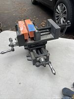 View of Pro Point cross sliding vice showing orange protective jaw covers, metal base, sliding mechanism, and clamping handle.