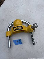 Reese Towpower universal coupler bar with yellow ball and locking keys inserted, placed on a white surface, tagged with a small blue label #2.