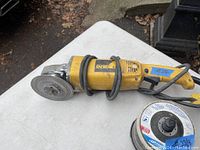 DeWalt angle grinder with grinding wheel attached on a white surface outdoors.