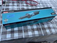 Photo of the boxed Makita 1/4 inch die grinder on a checkered surface.