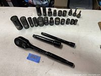 The main layout of all sockets arranged with ratchet and two extension bars on a white surface. Sockets display variety of sizes including 17, 14, 13/16 and others.