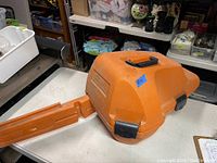 Closed orange hard plastic carrying case, top and side view