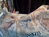 Photo showing portion of throw blanket with zebra, tiger, and lion images in detailed tapestry weave.