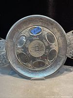 Full view of the vintage Passover metal Seder plate with visible handles and six recessed sections.