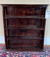 Front view showing three fixed shelves with dark brown finish and scalloped top trim.