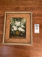 Front view of the framed floral oil painting on wooden floor, showing full artwork and frame.