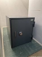 Front angled exterior view of gray safe showing door, handle and overall condition