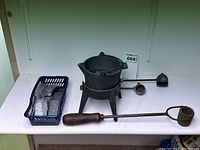Overview of lot showing soldering iron, cast iron pot with stand, solder blocks in basket