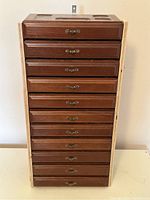 Front view of the vintage wooden jewelry box showing all 11 drawers with metal handles and the plywood side modifications.