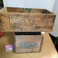 Two vintage wooden boxes stacked, top one marked Presto Nails with branding, lower one marked Lambert Marketing Co.