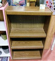 Front view of the brown wooden bookcase showing four shelves, wood grain pattern and overall rectangular shape.