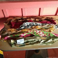 Top view of six assorted vintage scarves showing a variety of colors and prints lying on a table.