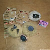 Lot of five 5-inch polishing bonnets and wire brush bonnets including metal attachment hardware, laid out on wood surface.