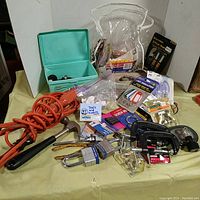Wide view of lot showing various hardware and tools including electric cord, hammer, toolbox, and packaged hardware items.