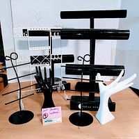Full view of 8 tabletop jewelry stands with various designs including hand shapes and bar holders, all arranged on a wooden surface against white background.