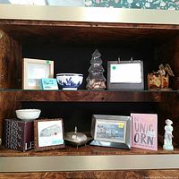 Shelf with 11 vintage collectibles including bowls, figurines, framed art, silver plate box, and decorative items.