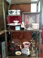 Full shelf showing all collectibles together including silver plated tiered holder, Christmas cups and plates, framed art and figurines