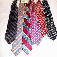 Six men's neckties laid out on white surface showing different patterns and colors from a top view.