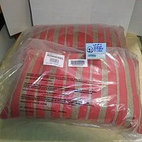 Two orange and gold striped pillows new in plastic packaging.