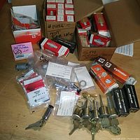 Overview of boxes with small lock rim cylinders, keys, and miscellaneous lock parts on wooden surface