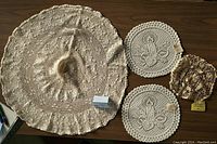 Full view of four vintage knit doilies laid flat on a wooden surface showing designs and sizes.