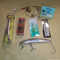 Lot of 6 fishing lures and hooks laid out on a surface showing packaging and loose items