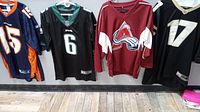 Four jerseys hanging: Denver Broncos #15, Philadelphia Eagles #6, Colorado Avalanche styled, and Colorado Buffaloes #17.