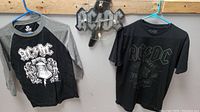 Photo showing two AC/DC T-shirts and battery operated wall clock with band logo