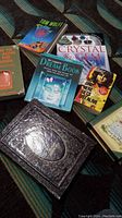 Seven vintage books arranged on a dark blanket including titles related to dreams, crystals, music, and survival.