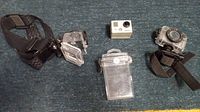 Wide view of all items showing GoPro Hero 2 camera, two waterproof cases, and head strap laid out on a carpeted floor
