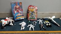 Full lot of Power Rangers and ThunderCats action figures and toys seen arranged on a blue carpeted floor against a grey wall baseboard.