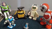 Buzz Lightyear, Wall-E, Alfie playing robot, and Love Machine dancing robot on blue surface